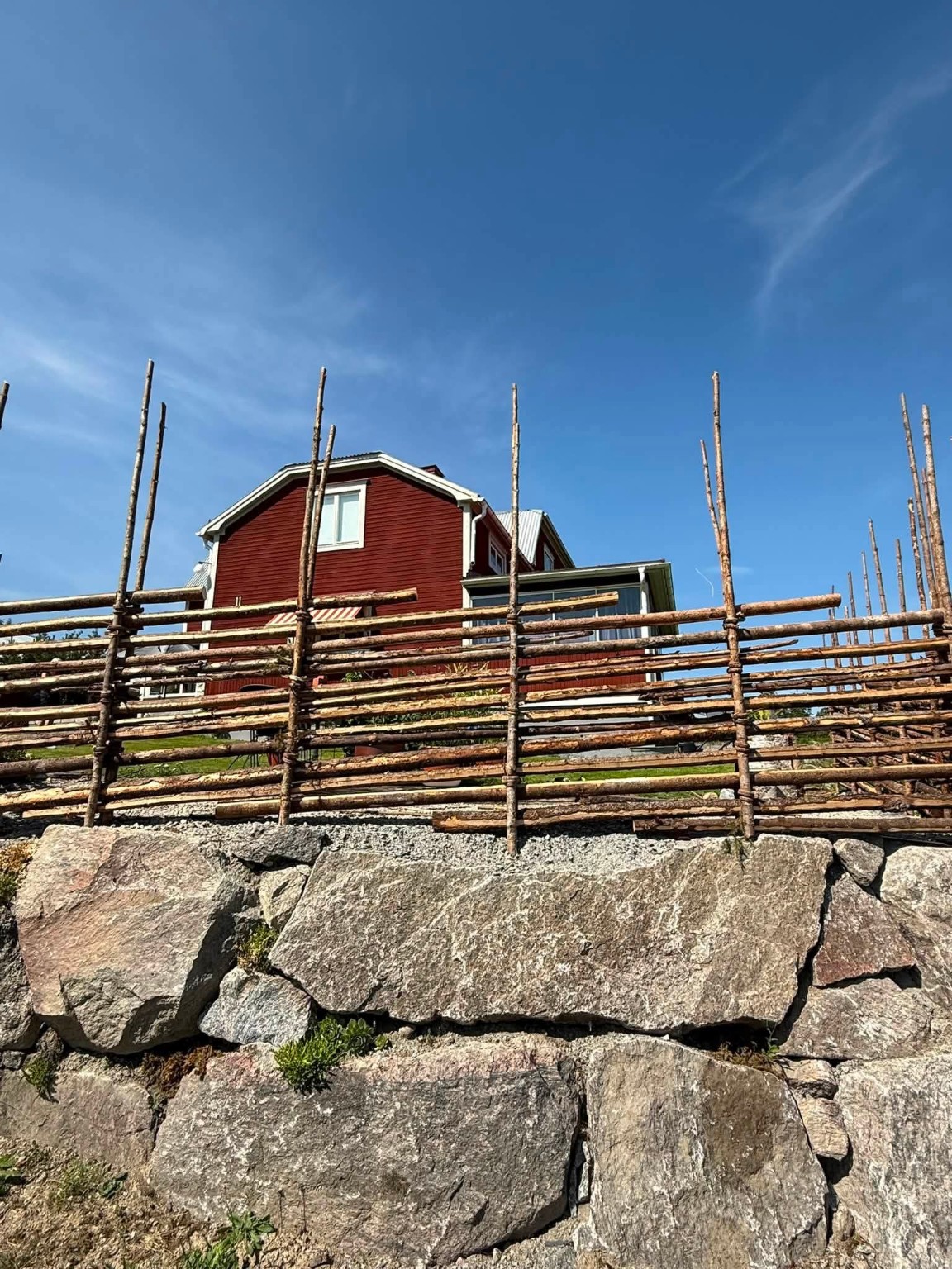 Gärdsgård framför ett rött hus